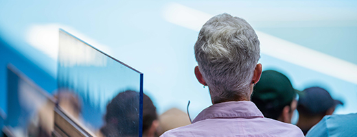 Image of senior man from behind at a crowded lecture hall